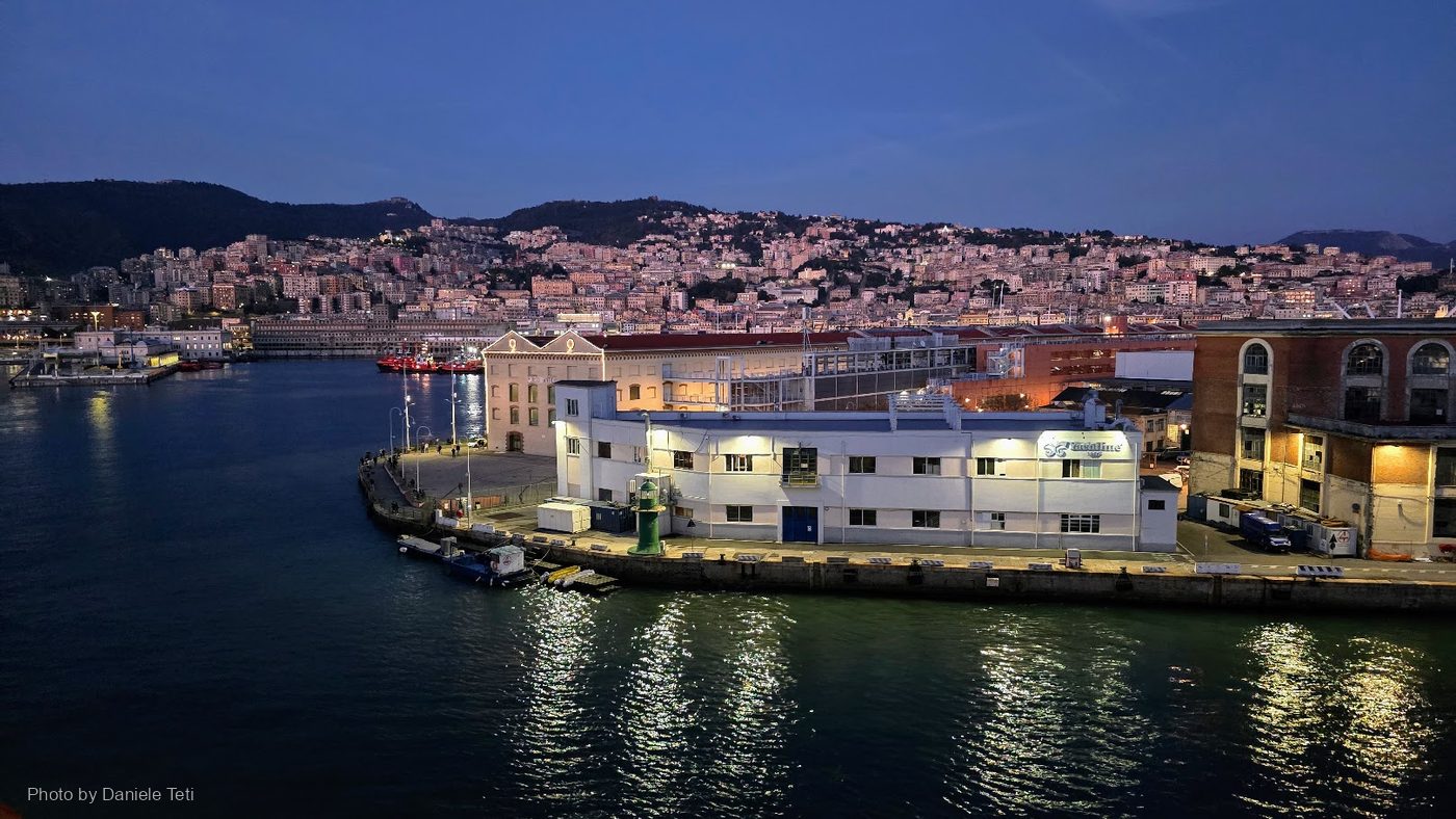Il porto di Genova all'ora blu, con la città che sale sulle colline dietro le banchine